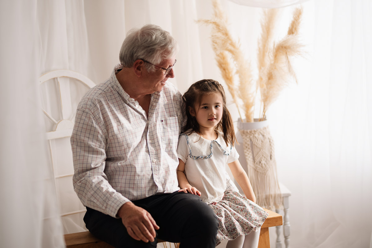 Grandfather sitting on a bench with his granddaughter for their family photography in Oxfordshire