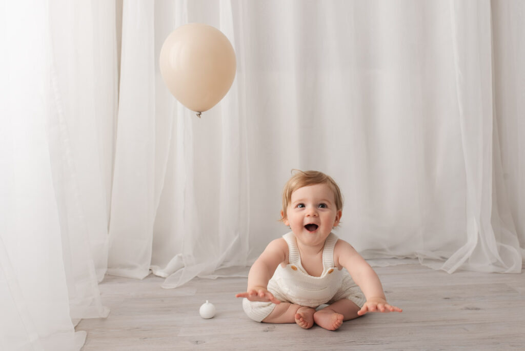 1 year old boy leaps towards the photographer as he gets ready to crawl away