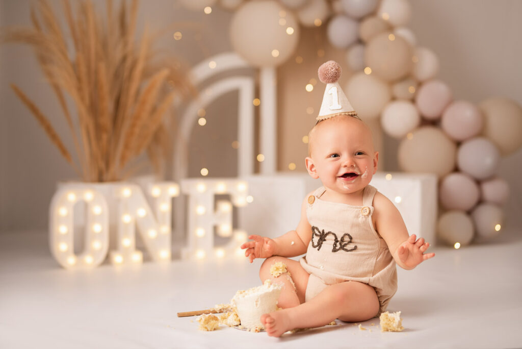 One year old boy having smashed his cake smiles for the family photographer in their Oxfordshire studio