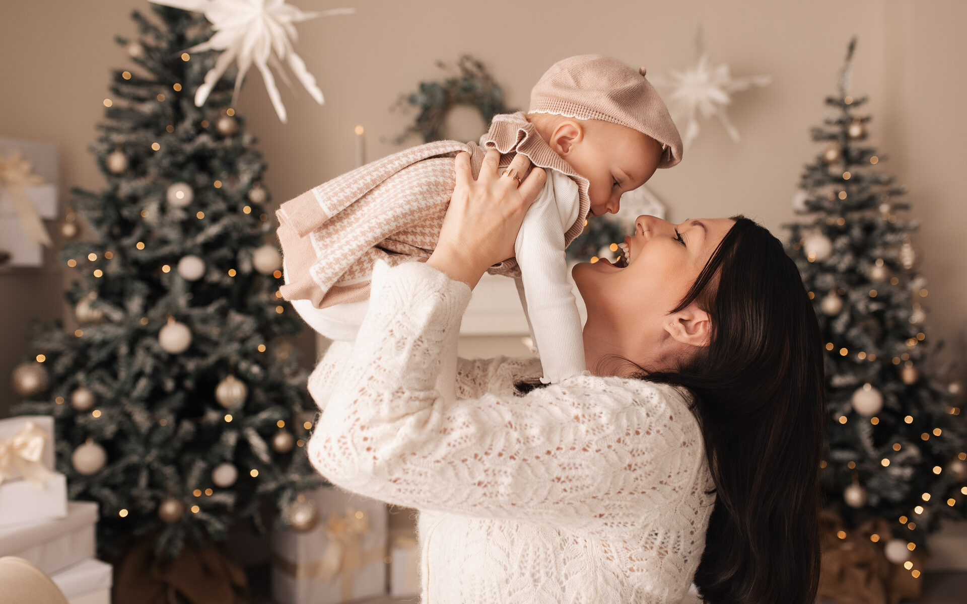 Mother holds her daughter in the air during their family Christmas photoshoot