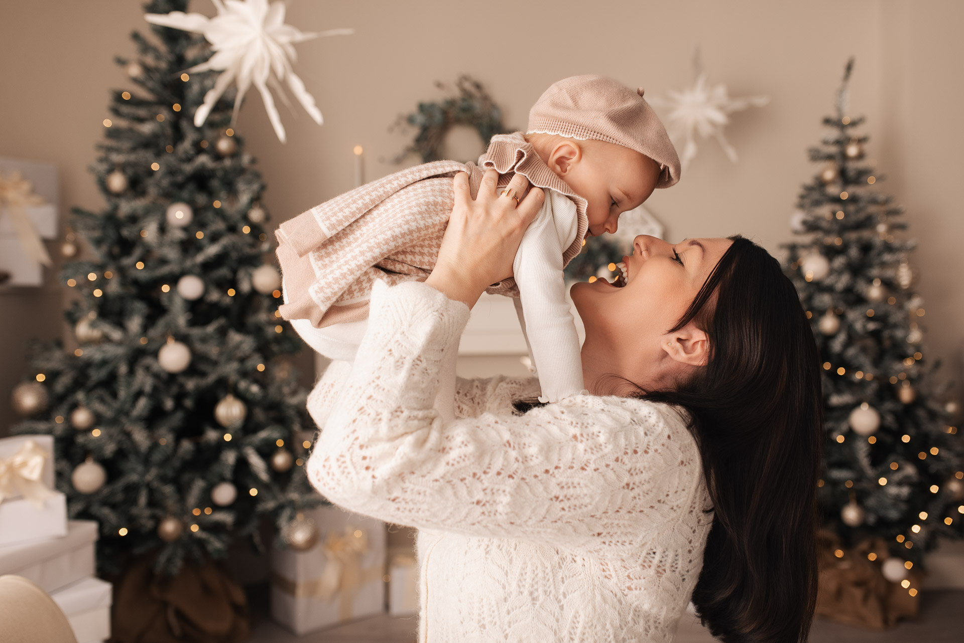 Mother holds her daughter in the air during their family Christmas photoshoot