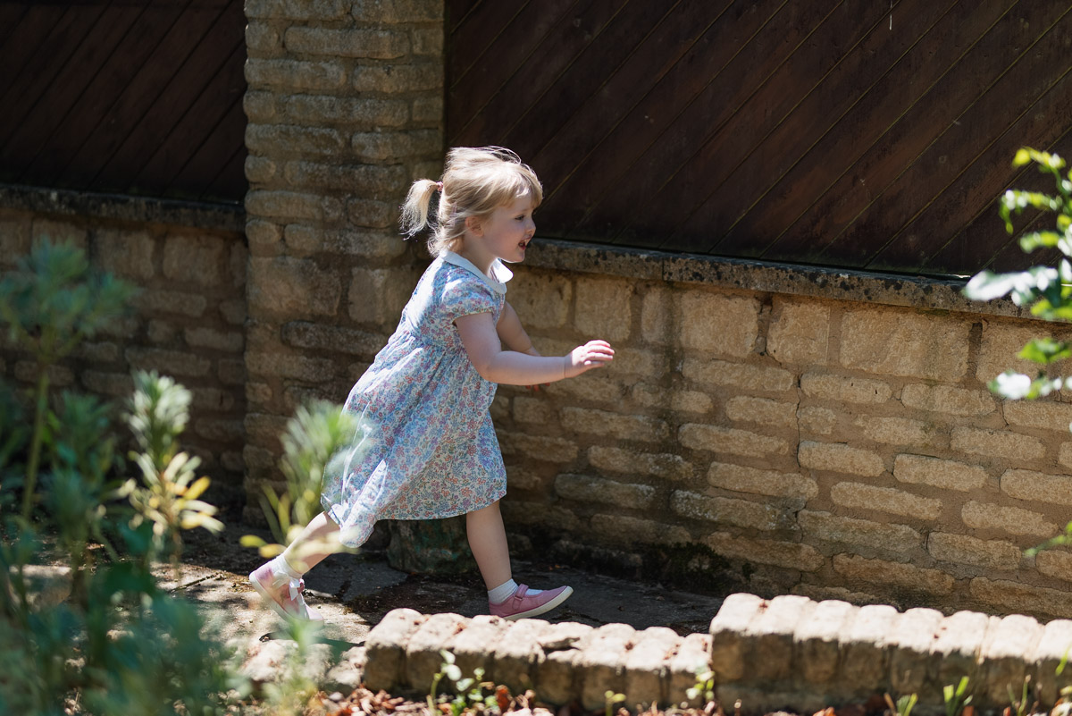 Little girl running around her garden trying to avoid the photographers camera