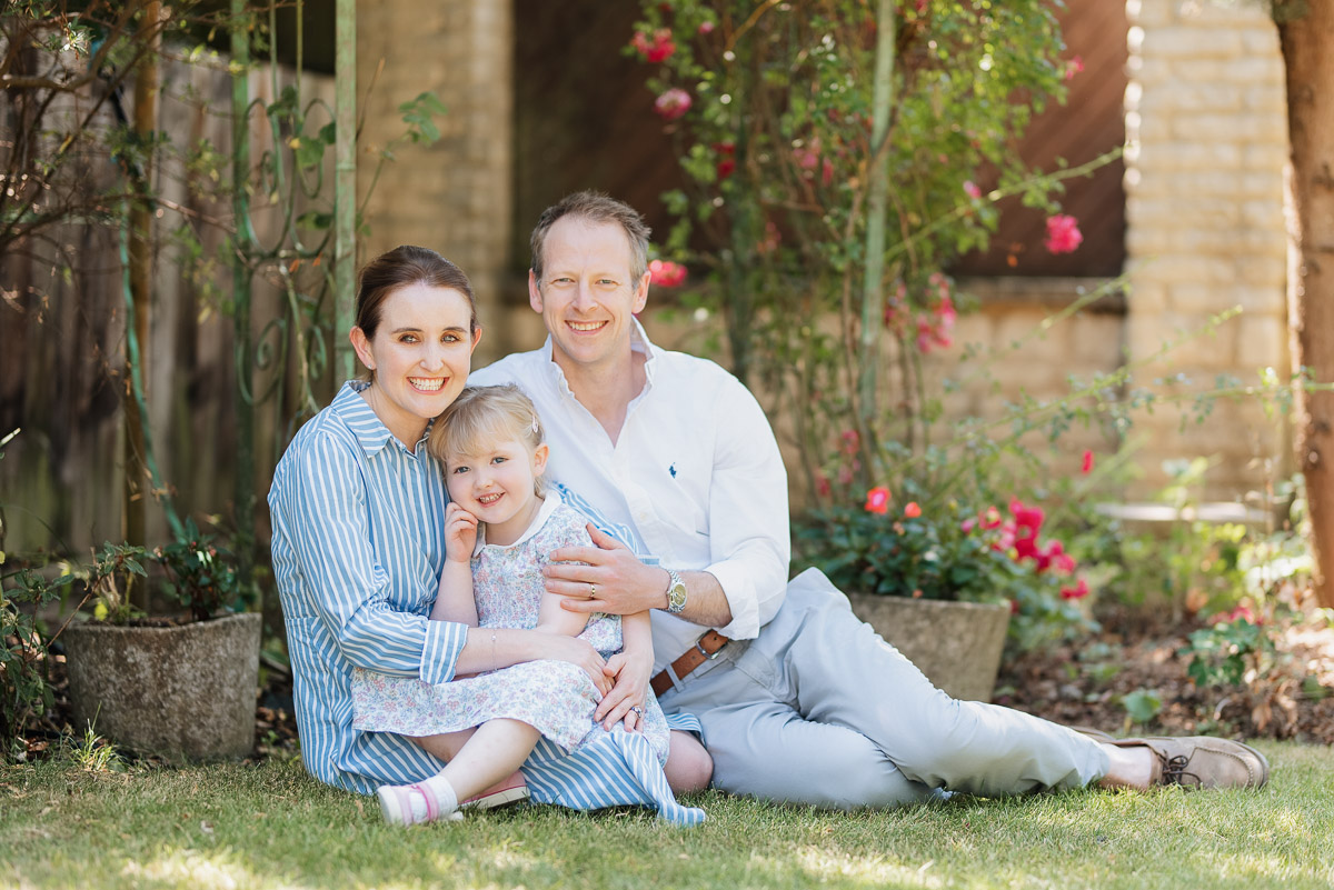 Family of three sit on the grass in their garden in the centre of Oxford