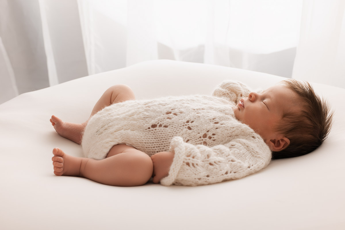 Baby girl asleep on her back on the photographers beanbag during her first photoshoot