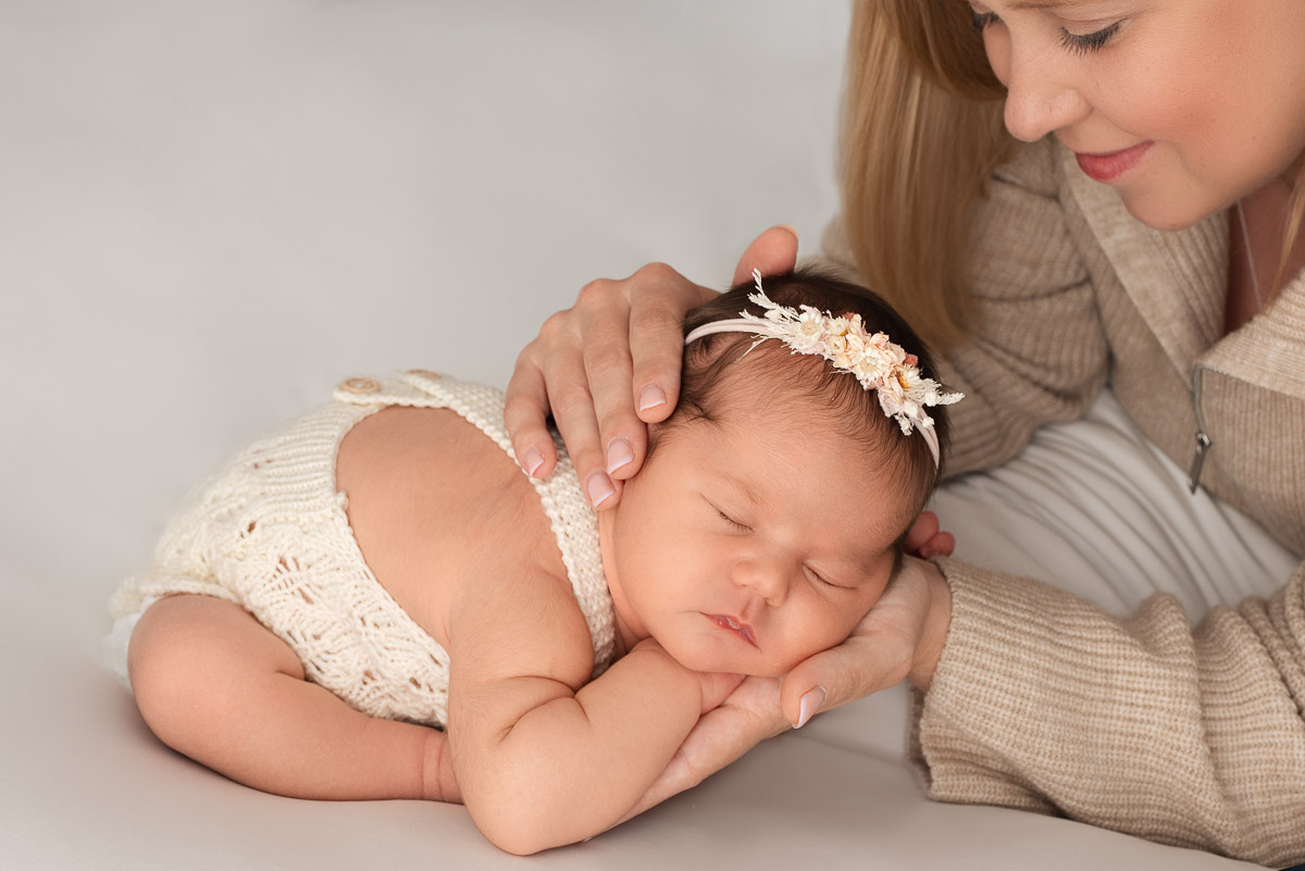 Baby girl sleeps with her head on mummy's palm. Mummy is in the edge of the shot